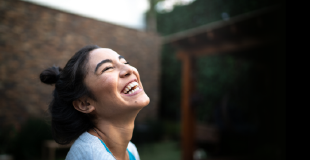 Young woman of east asian descent laughing and looking up at the sky in her garden
