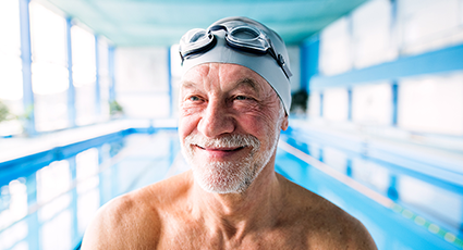 Older man wearing swimming cap by a pool