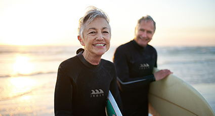Man and woman holding surf boards by the sea
