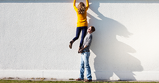 Man lifting woman over a wall