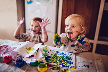 Two children painting with their hands