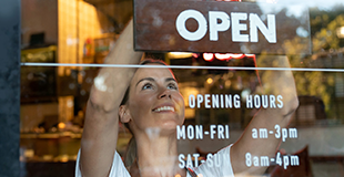 Women in café hanging up open sign