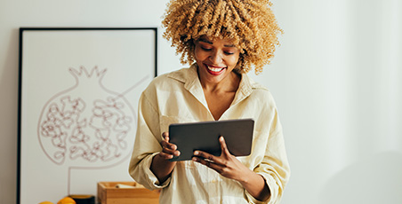 Young black women smiling whilst using her tablet device