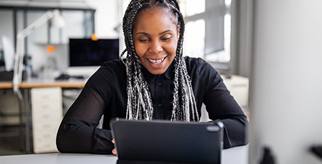 A women of colour smiling whilst on a laptop