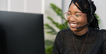 A young black woman wearing a headset on her laptop during a meeting