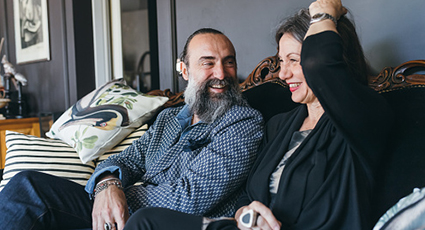 Middle aged couple sitting on a sofa and smiling.