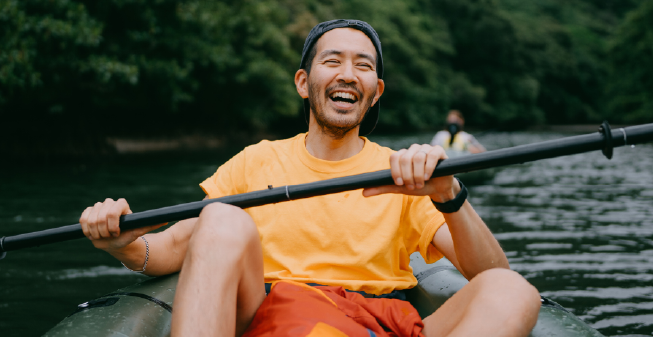 Young man of east asian descent smiling whilst in a canoe on the water