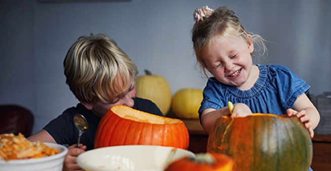Two children carving pumpkins