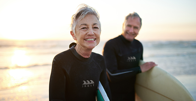 Man and woman holding surf boards by the sea