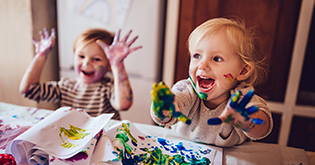 Two children painting with their hands