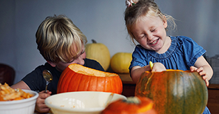 Two children carving pumpkins