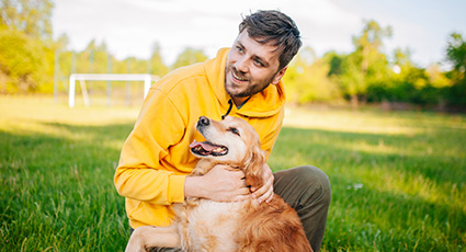 Man smiling and petting a dog in the garden